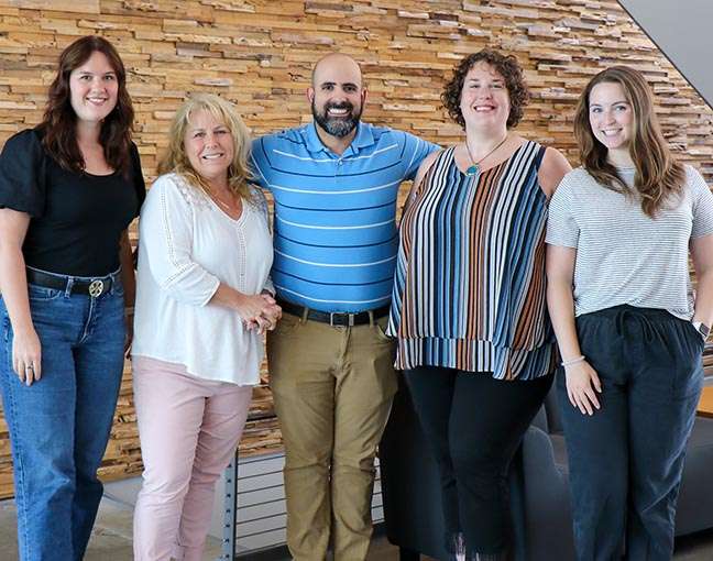 Members of the Experiential Programs team -- Megan Graettinger, Jean Walsh, Alex Andrade, Ashley Sawyer and Sam Dilocker -- pose for a group photo.